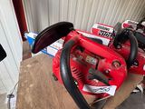 deux tronçonneuses rouges posées sur une caisse devant un immeuble