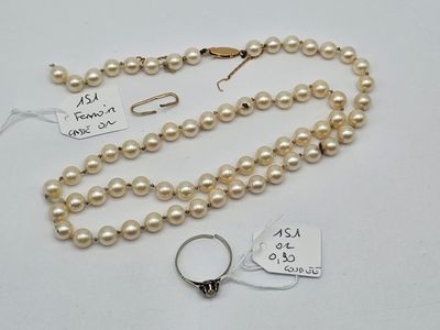 a close up of a necklace with pearls and a ring on a table