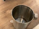 a large metal bucket sitting on the floor next to a box