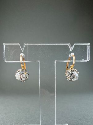 pair of gold and diamond earrings on display on clear acrylic stand