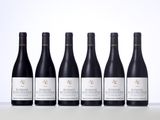 six bottles of red wine lined up on a table