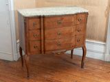 a marble top chest of drawers in the corner of a room