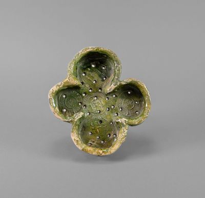 a close up of a green flower shaped object on a gray surface