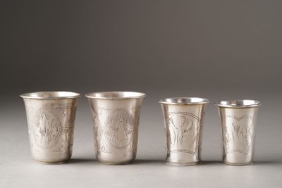 four silver cups with designs on them are lined up on a table