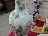 un grand vase posé sur une table sur laquelle se trouvent des assiettes