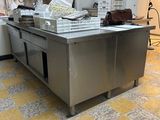 une cuisine avec un grand îlot en inox au milieu de la pièce