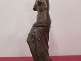 bronze statue of a woman holding a vase on a red carpet