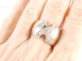 a woman ' s hand holding a silver ring with a cross on it