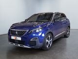 La voiture bleue est garée dans une grande pièce au sol noir.