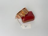 un sac à main rouge et une bague en or sur un fond blanc