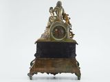 a clock with a statue on top of it on a table