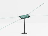 a glass sculpture on a metal stand on a white surface