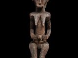 une image représentant une statue en bois d'un homme assis sur une surface noire