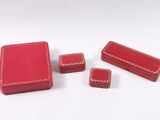 three small red boxes with red stitching on them sitting on a white surface