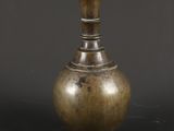 un vase ancien en laiton sur fond noir, avec un arrière-plan sombre