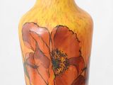 a yellow vase with orange flowers painted on it