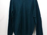 a green sweater hanging on a white wall next to a hanger