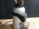 a blender sitting on a wooden table with a cup of coffee