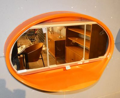 un miroir ovale de couleur orange accroché au mur d'une pièce