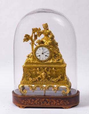 une horloge en or sous un dôme de verre sur une table