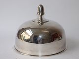 une assiette en argent ornée d'une clochette, posée sur un fond blanc