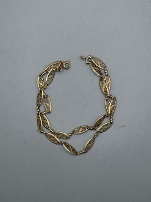 a close up of a gold bracelet on a white surface