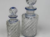 two clear glass bottles with blue tops sitting on top of a white surface