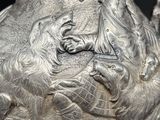 a silver vase with a picture of a man and a dog on it