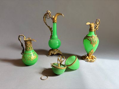 trois vases verts et deux vases dorés posés sur une table