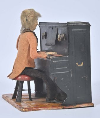 a doll sitting at a piano with a teddy bear on it