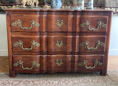 une commode en bois avec de nombreux tiroirs, sur laquelle est posé un vase
