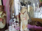 une figurine représentant une femme, placée sous une cloche en verre sur une table