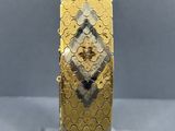 a close up of a gold and silver bracelet on a clear stand