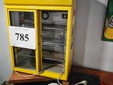 un distributeur automatique jaune posé sur une table en bois, près d'un mur