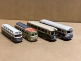 quatre petits bus en plastique posés les uns à côté des autres sur une table
