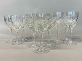six crystal wine glasses are lined up on a white surface