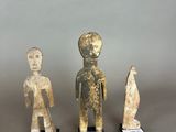 three figurines of a man and a woman on stands