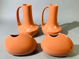 trois vases orange posés les uns à côté des autres sur une table
