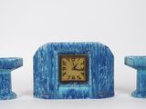 une horloge bleue posée à côté de deux bougies et d'un bougeoir