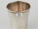 a silver cup with a tag on it sitting on a white surface