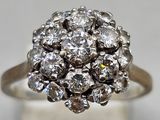 a close up of a diamond cluster ring on a white surface