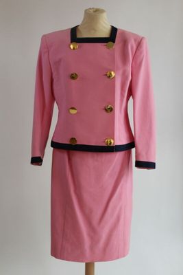 robe rose et noire avec des boutons dorés, posée sur un socle de mannequin