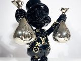 une figurine noire et dorée représentant un homme tenant deux cloches