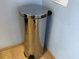 a metal trash can in the corner of a room