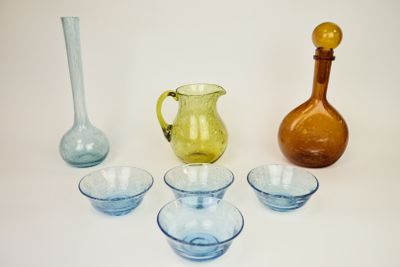 plusieurs vases et bols en verre de différentes couleurs posés sur une surface blanche