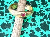 a gold ring with a ruby stone on it sitting on a stick
