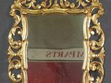 un miroir avec un cadre doré posé sur une surface grise