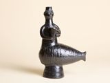 une image représentant un vase noir surmonté d'un oiseau