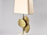 a gold leaf lamp with a white shade on top of it
