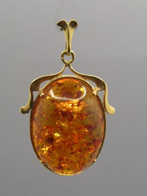 an image of a gold pendant with a large amber stone